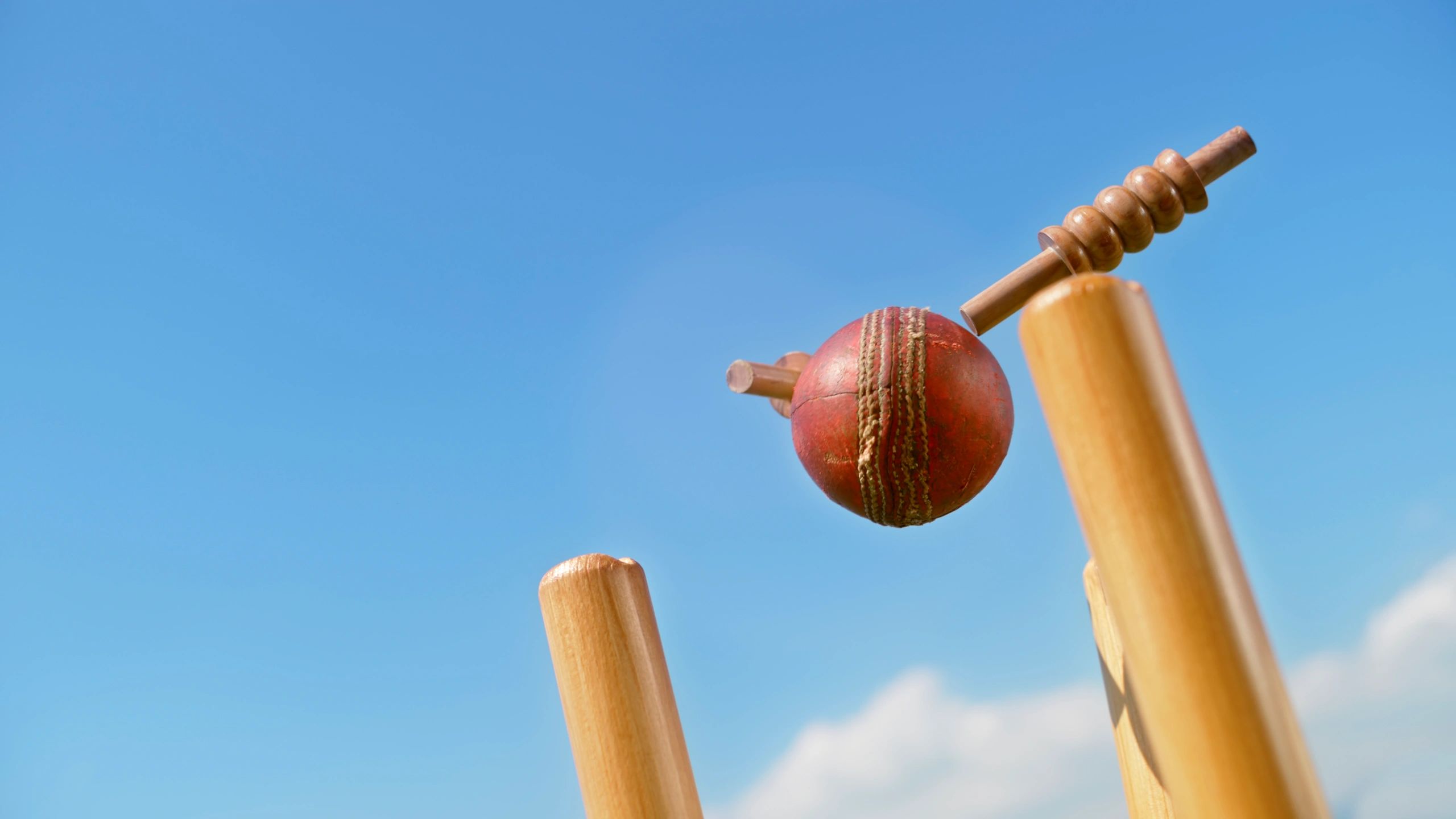Cricket ball hitting the stumps and knocking off the bails