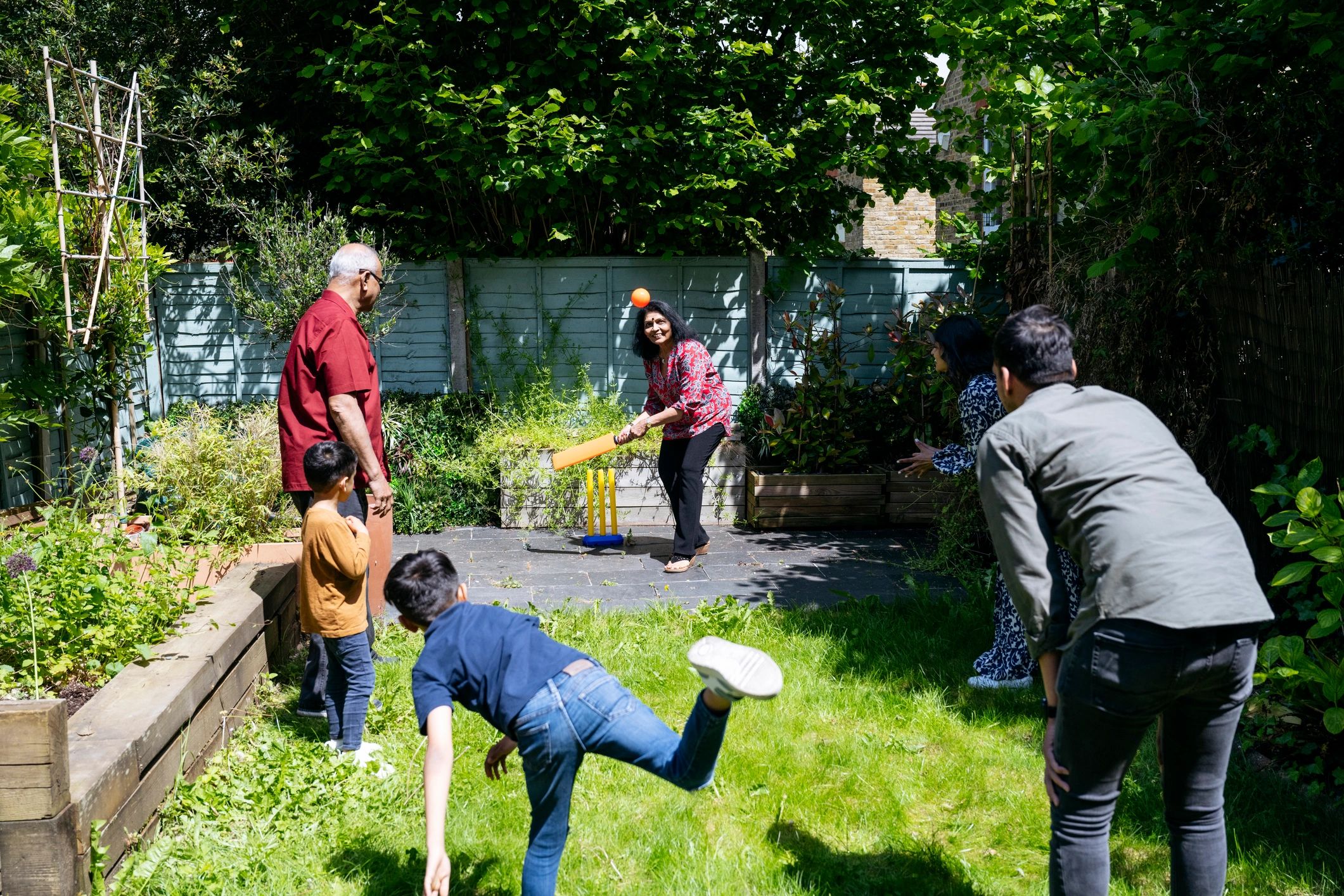 Family playing cricket in a garden