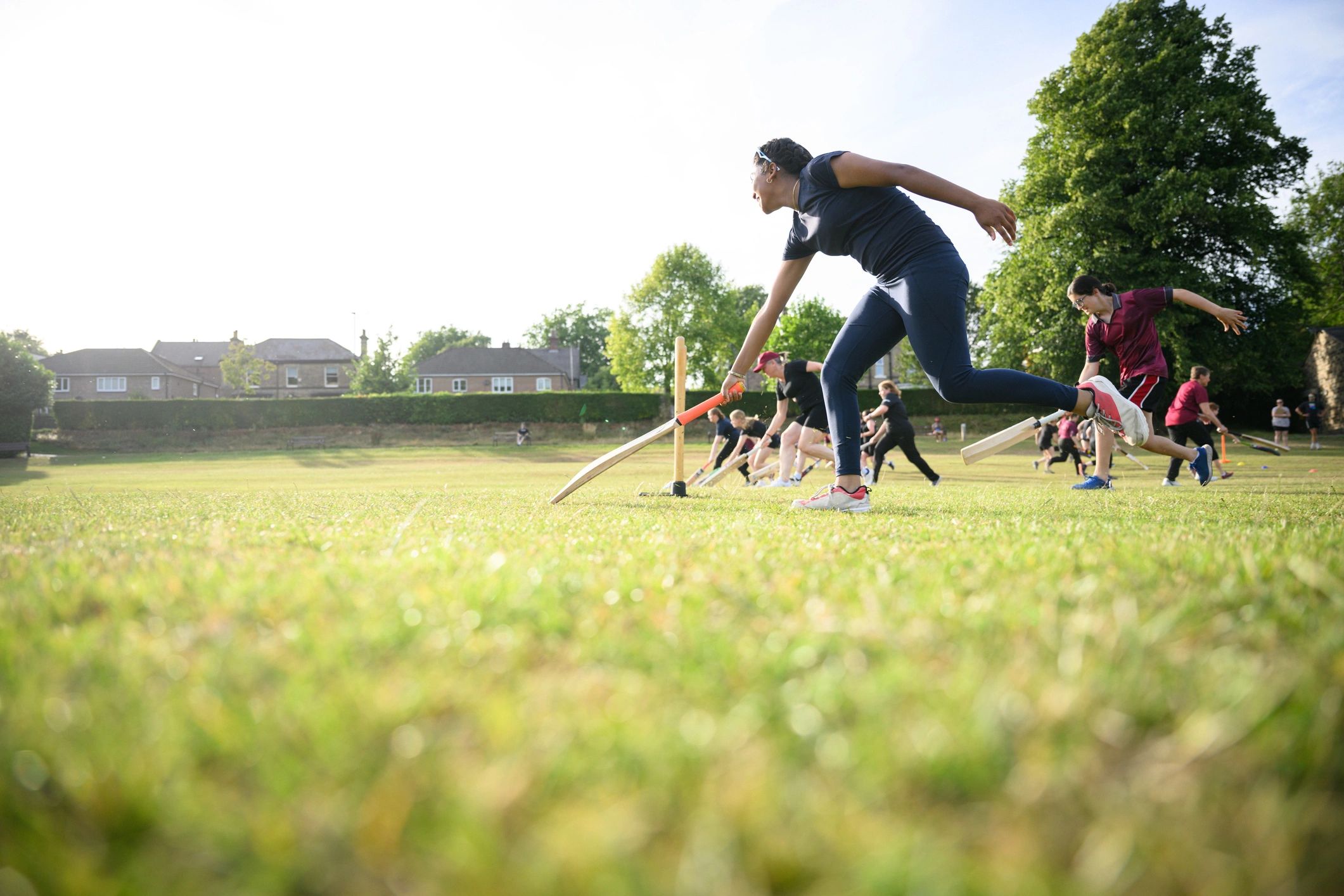 Players running drills with cricket bats during training