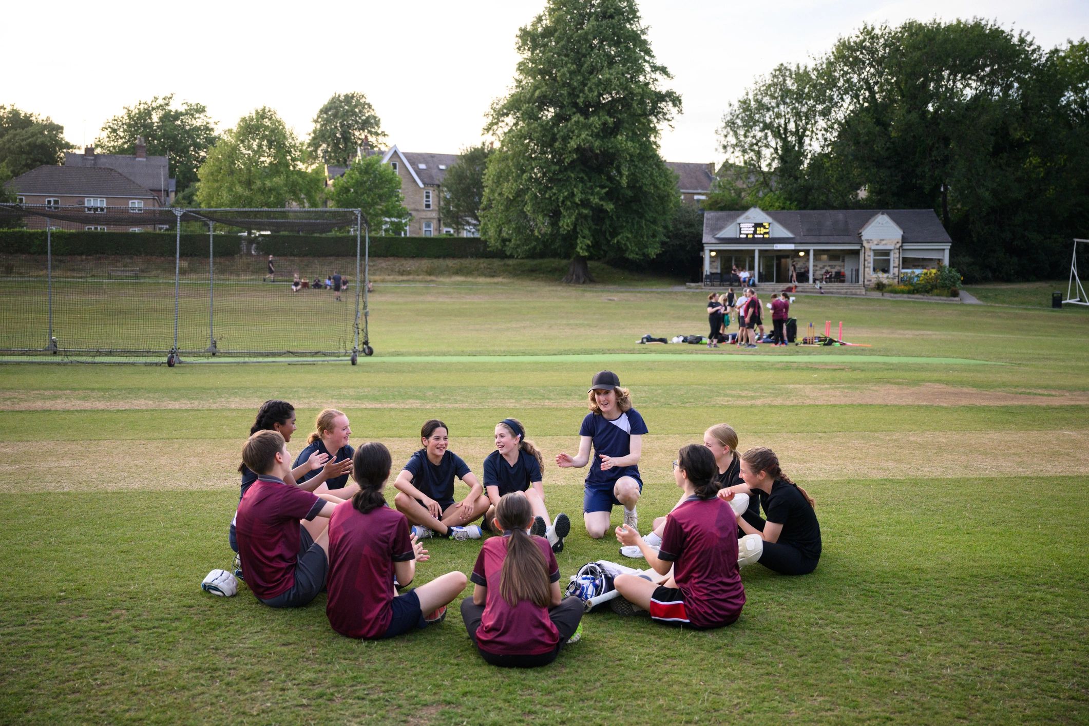 Coach talking to a youth cricket team in a huddle