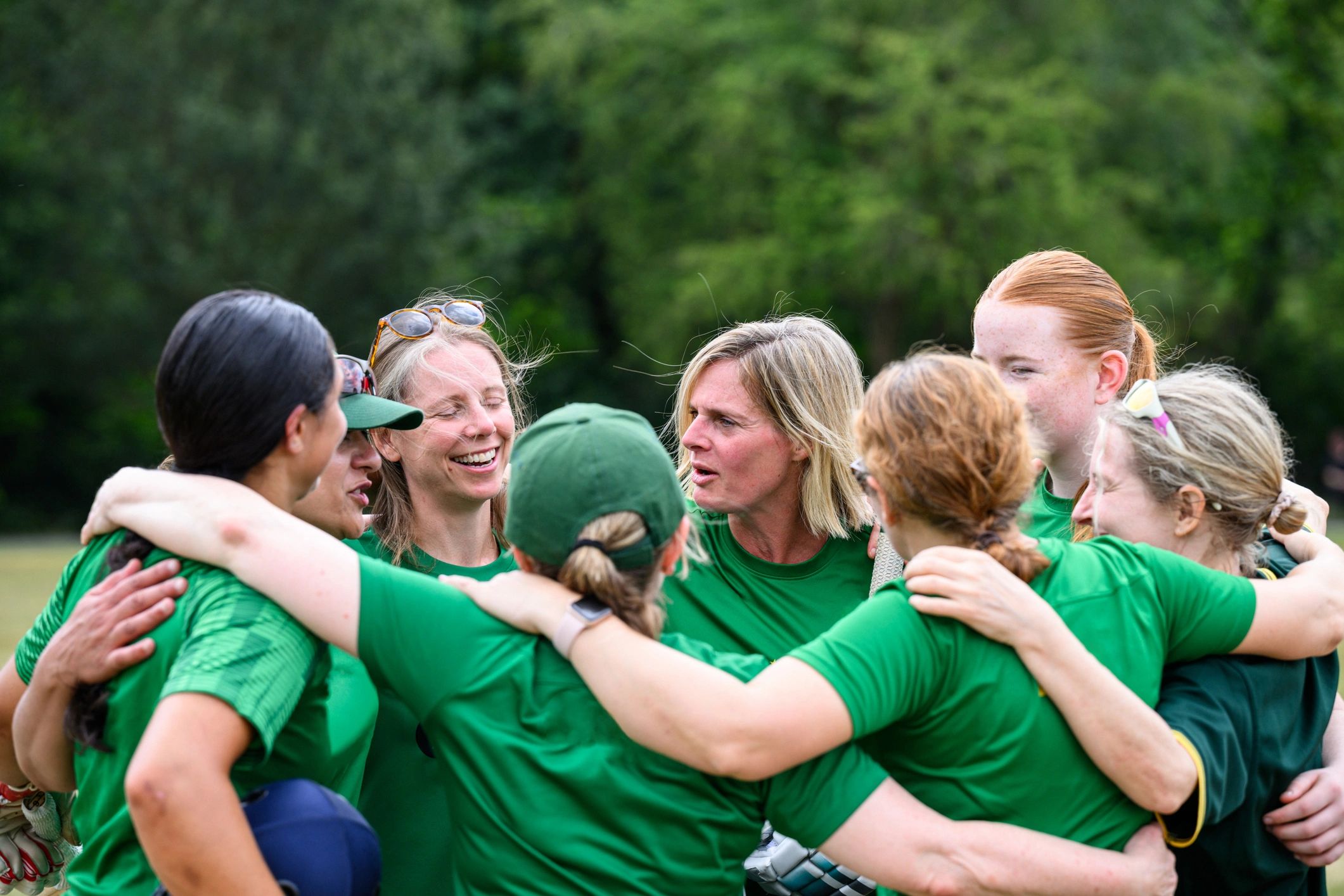 Women and girls sports team standing in a huddle after a match