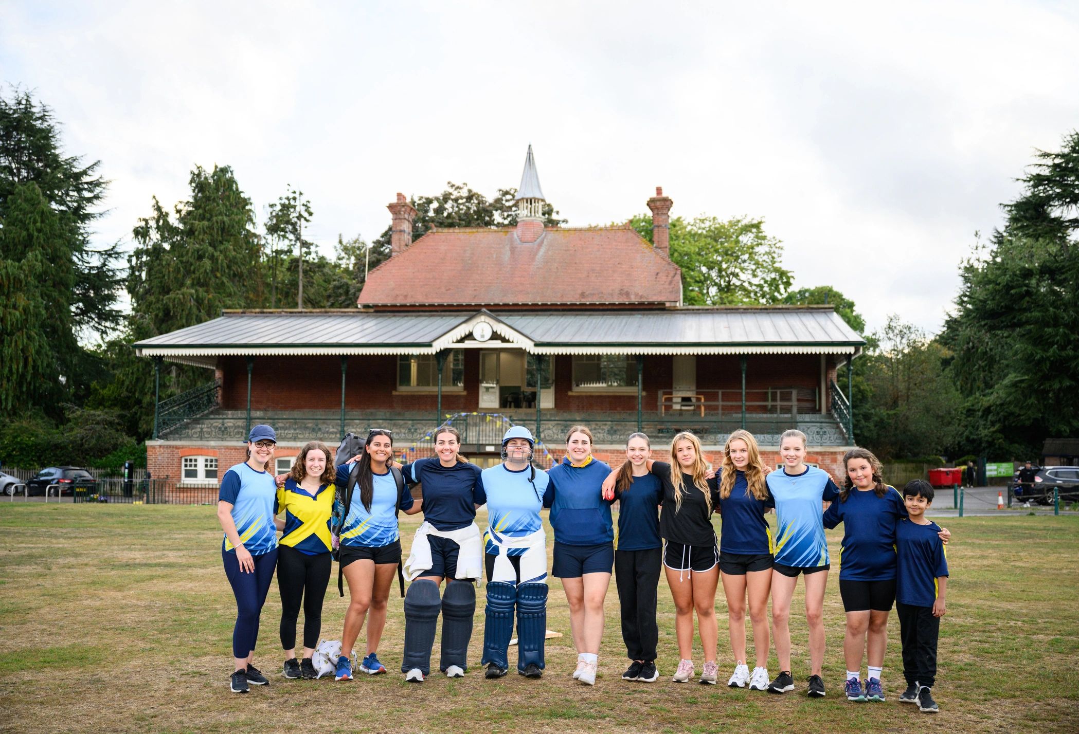 Women and girls cricket team standing together on the field