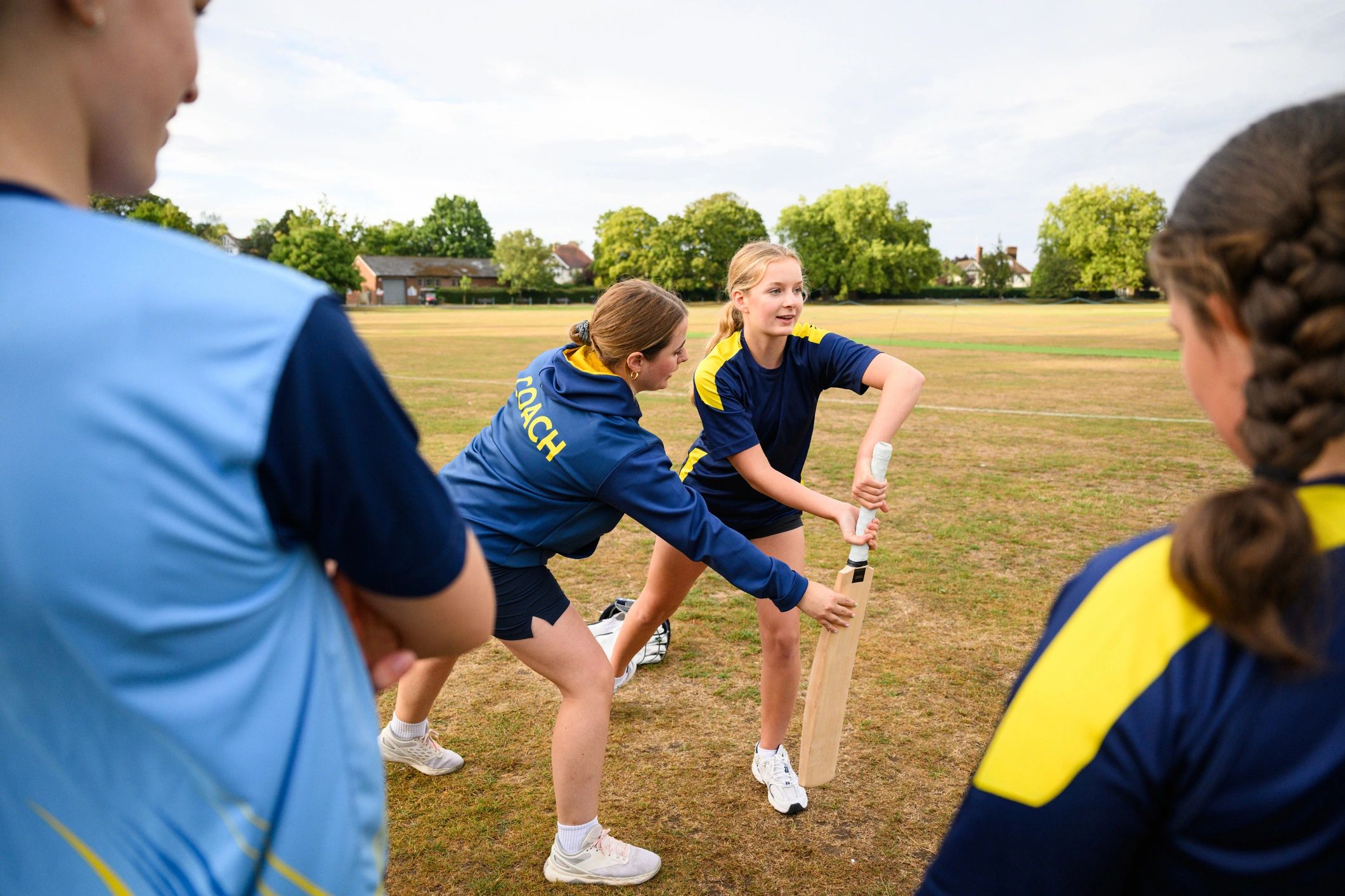 Coach guiding a young player’s batting position during practice