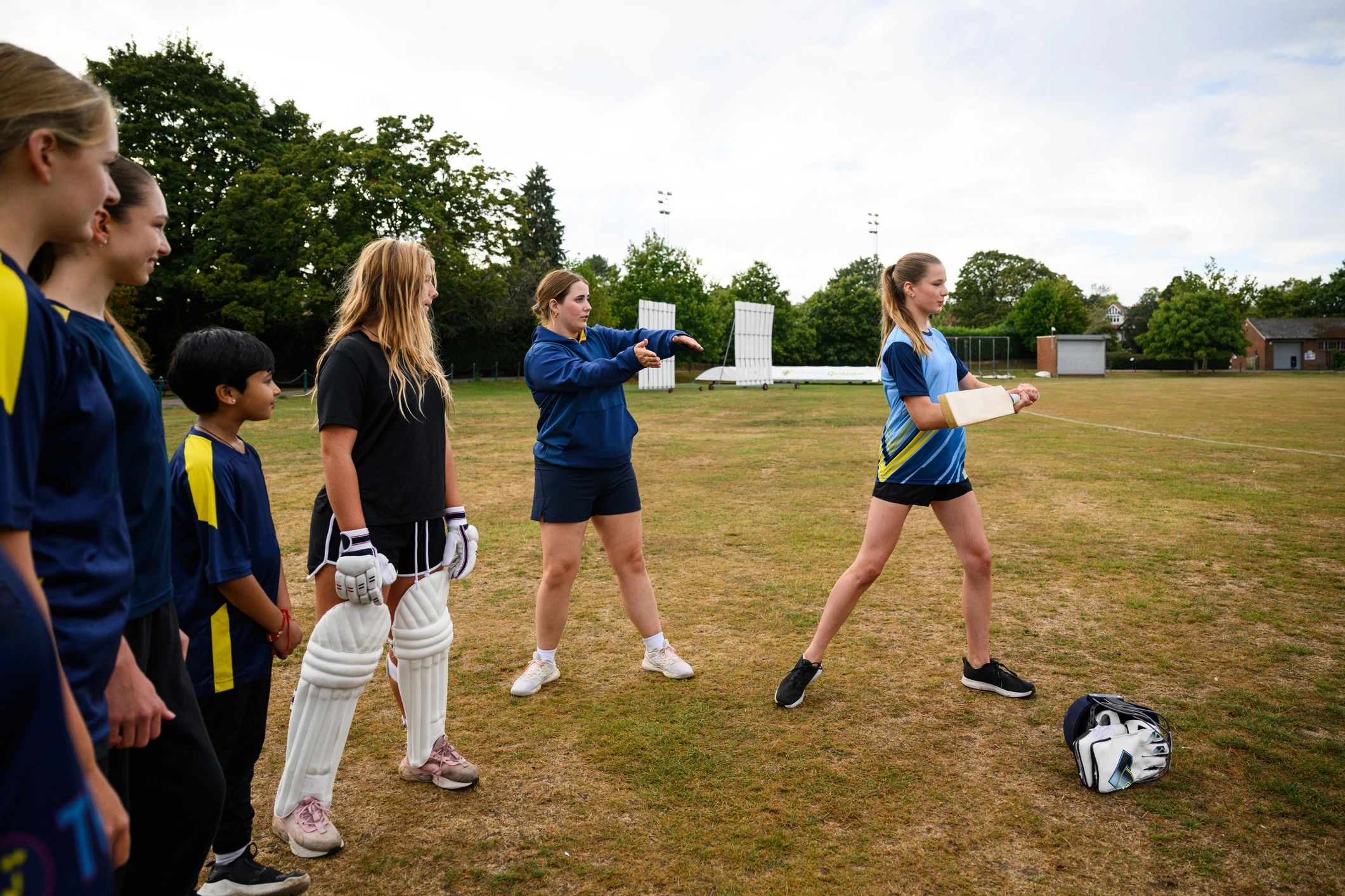 Youth cricket coaching and batting practice on a field