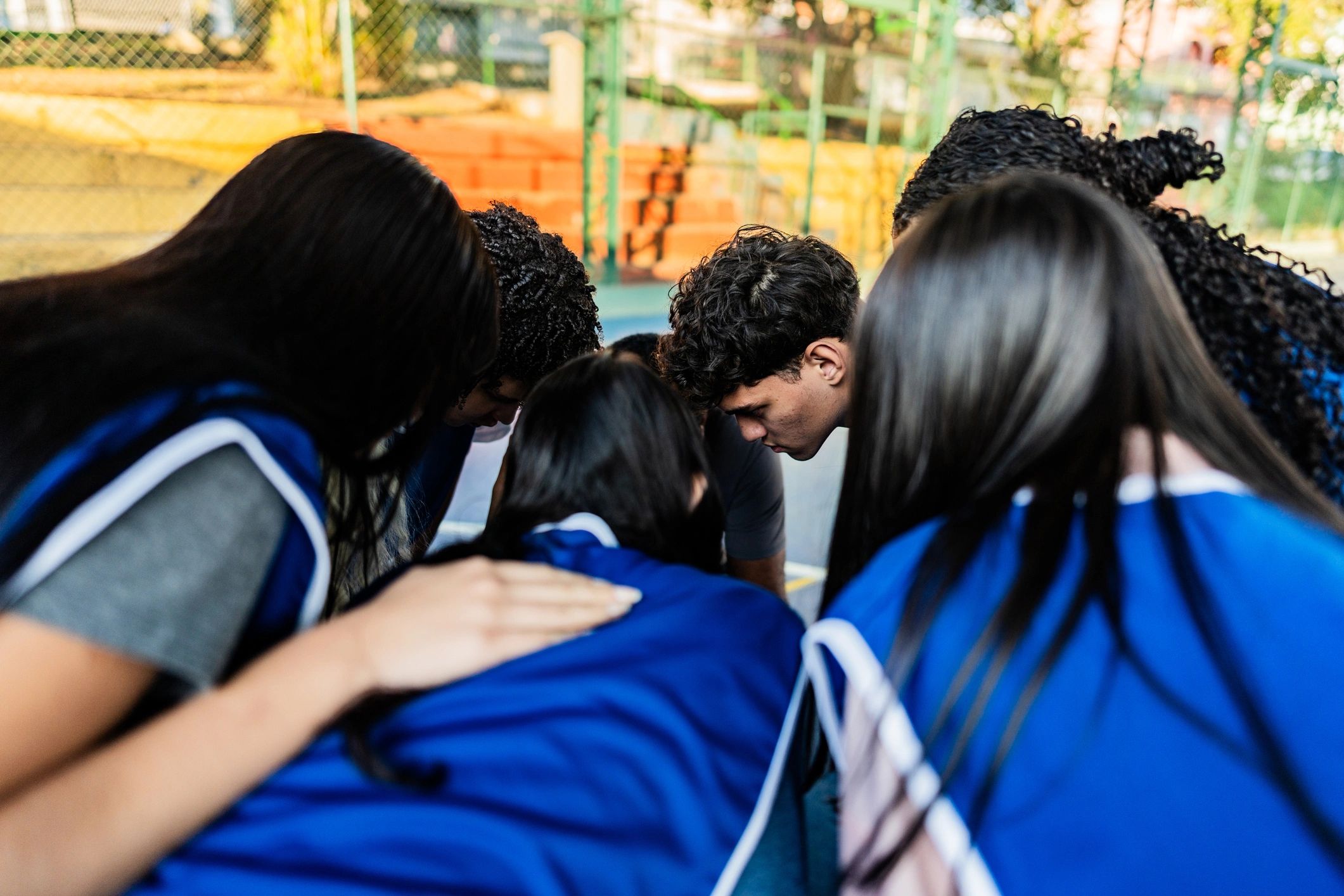 Students listening to a coach on an outdoor sports court