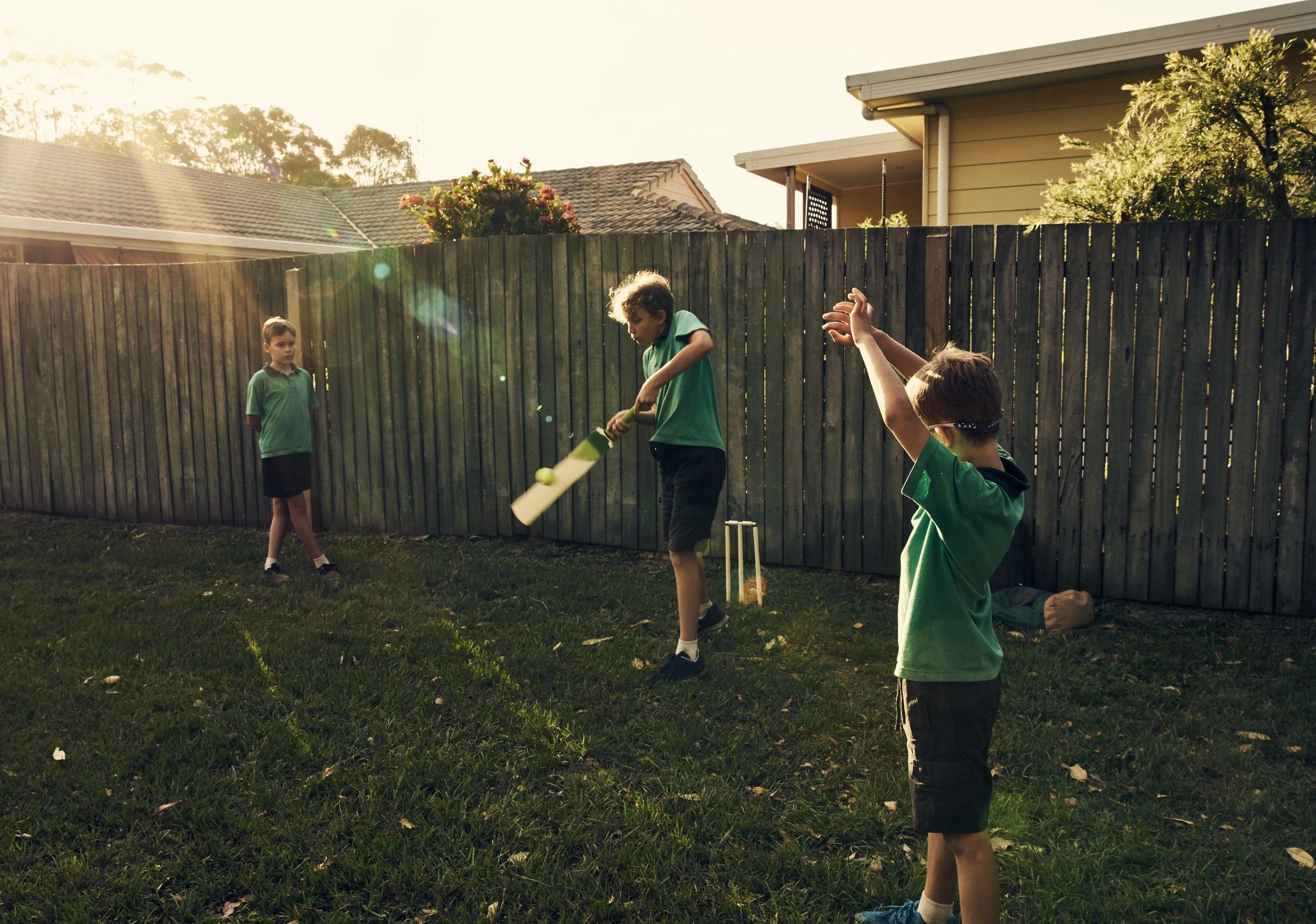 Boys playing cricket in a backyard